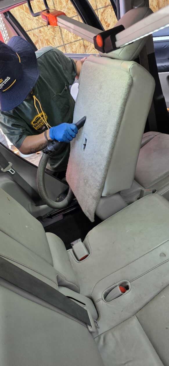 Detailer vacuuming and deep cleaning a vehicle interior