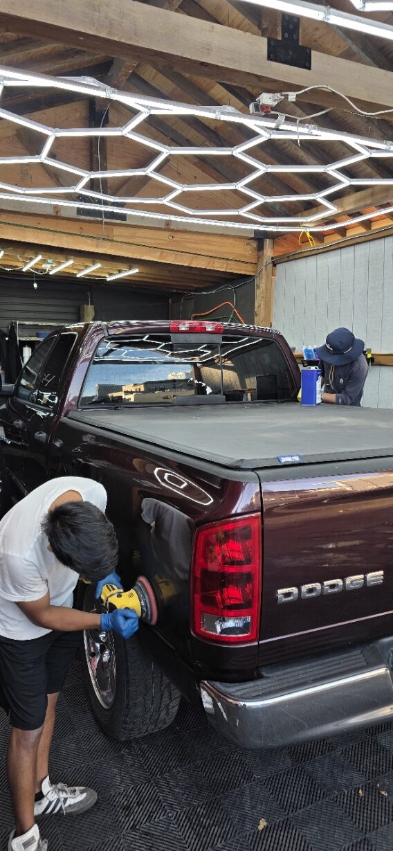 Two detailers polishing a maroon pickup truck