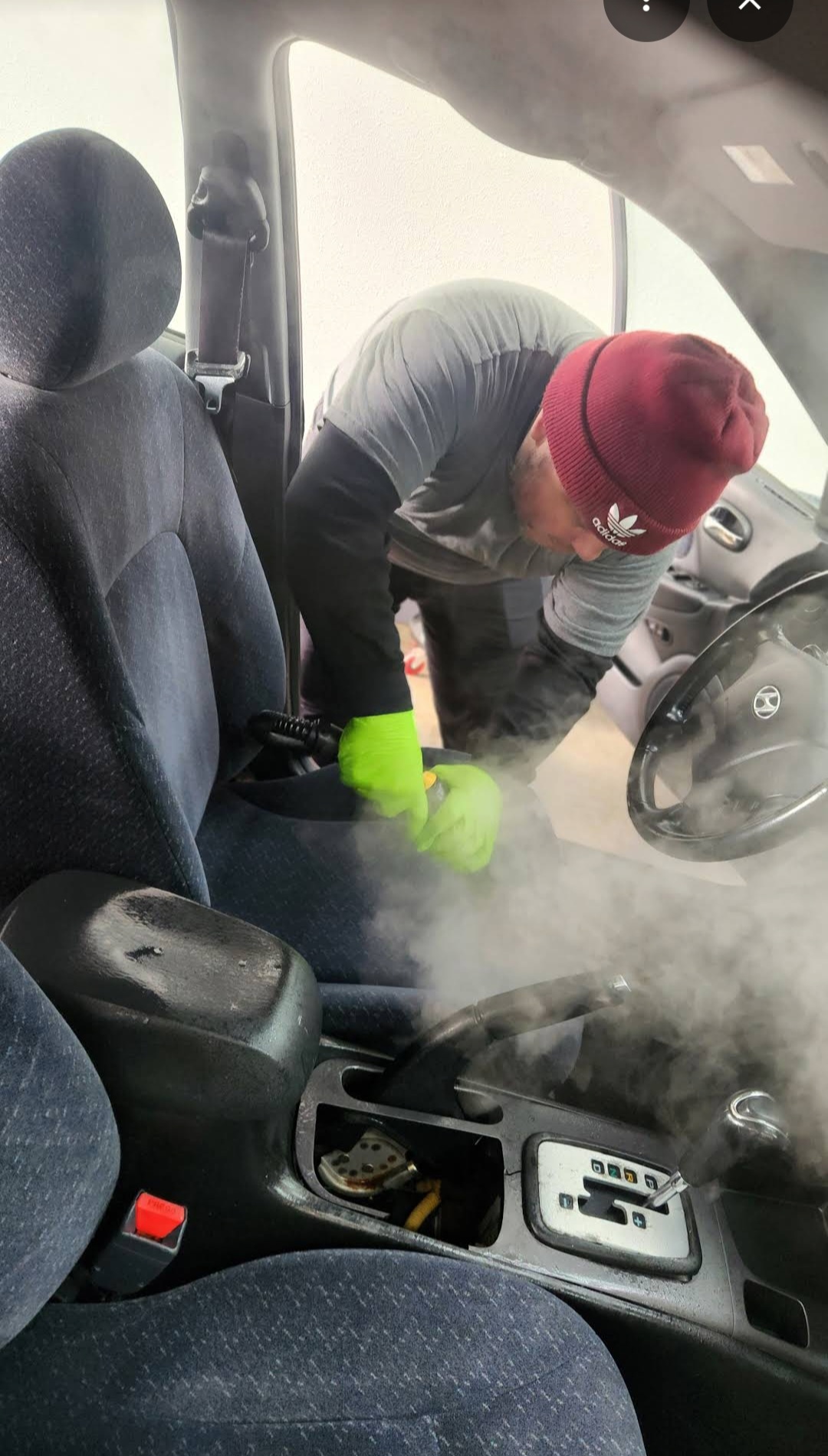 Detailer steam cleaning a car seat